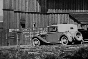 Na výřezu z předcházející pohlednice můžeme vidět před automobilem Tatra ceny obědů a piva.